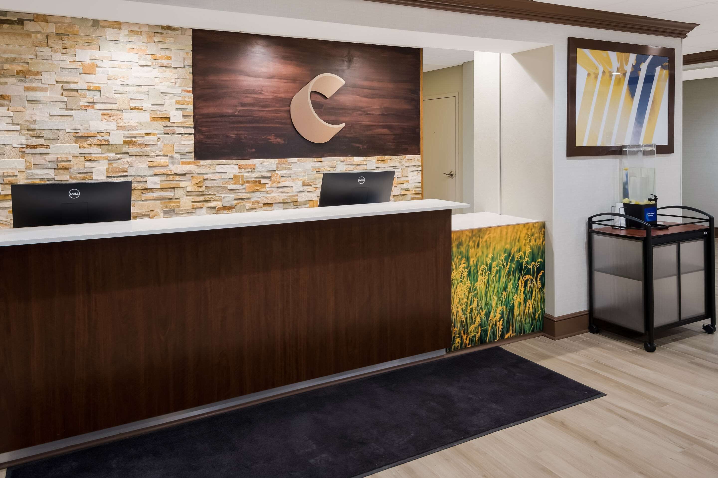 A reception desk with a stone wall, a large 'C' logo, and a laptop.
