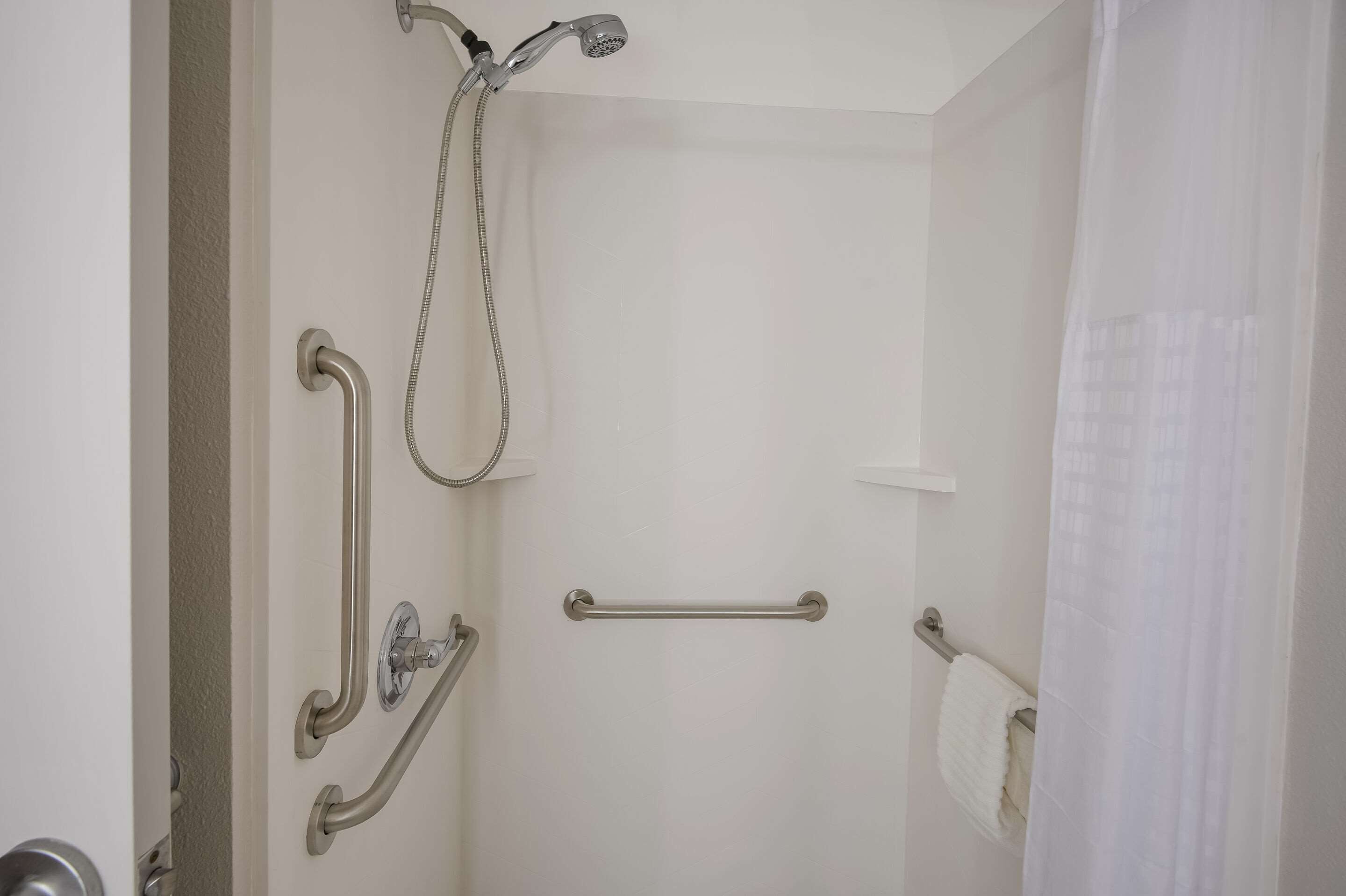 Une salle de bain équipée d’une douche, de barres d’appui et d’un porte-serviettes.