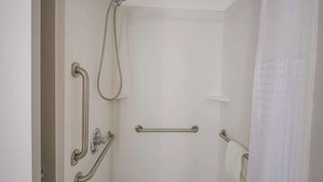 Une salle de bain équipée d’une douche, de barres d’appui et d’un porte-serviettes.