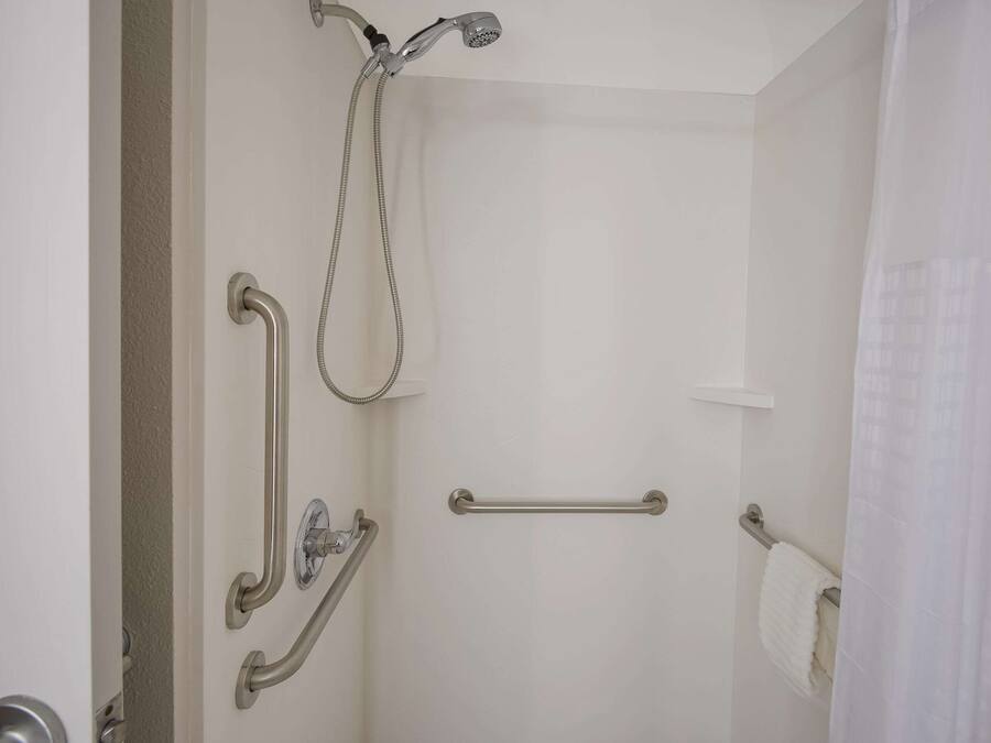 Une salle de bain équipée d’une douche, de barres d’appui et d’un porte-serviettes.