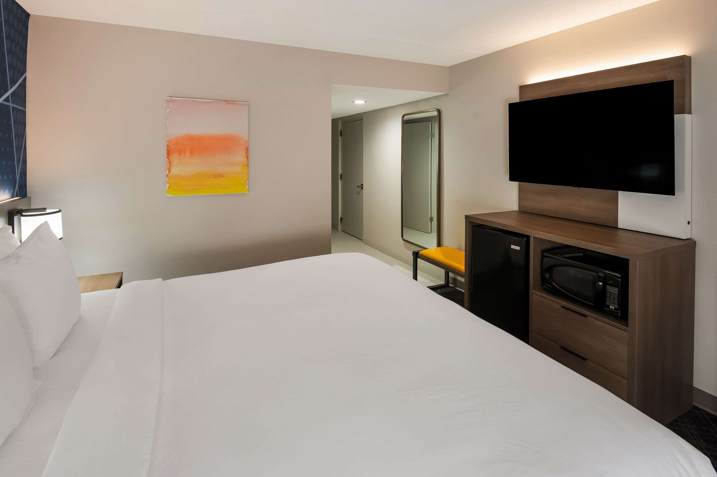 A hotel room with a large bed, a flat-screen TV, a microwave, and a small seating area.