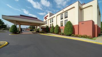 A hotel with a covered entrance, a clear sky, and a well-maintained parking lot.