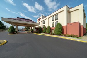 A hotel with a covered entrance, a clear sky, and a well-maintained parking lot.