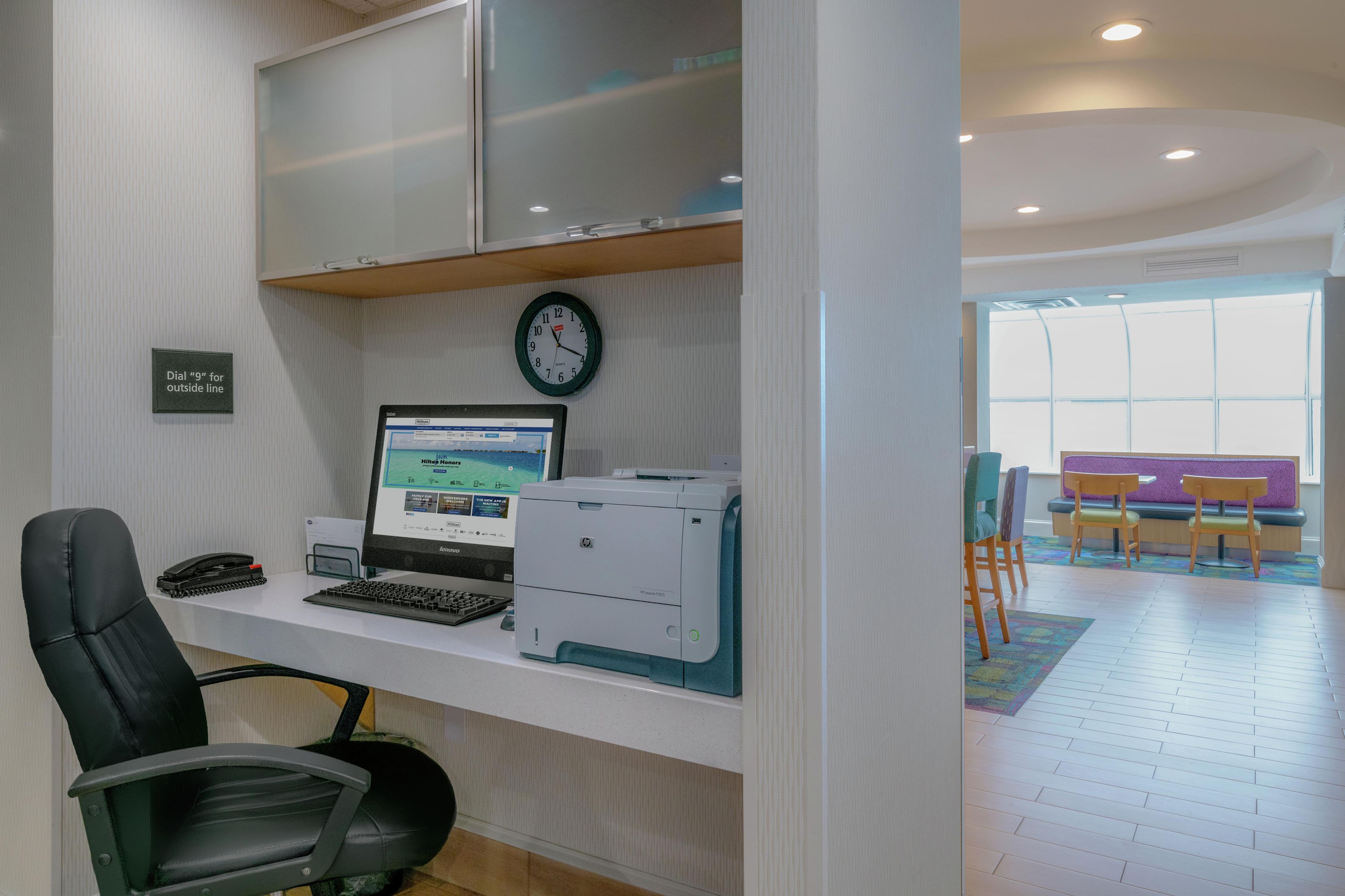 A modern office with a desk, computer, printer, and chairs.