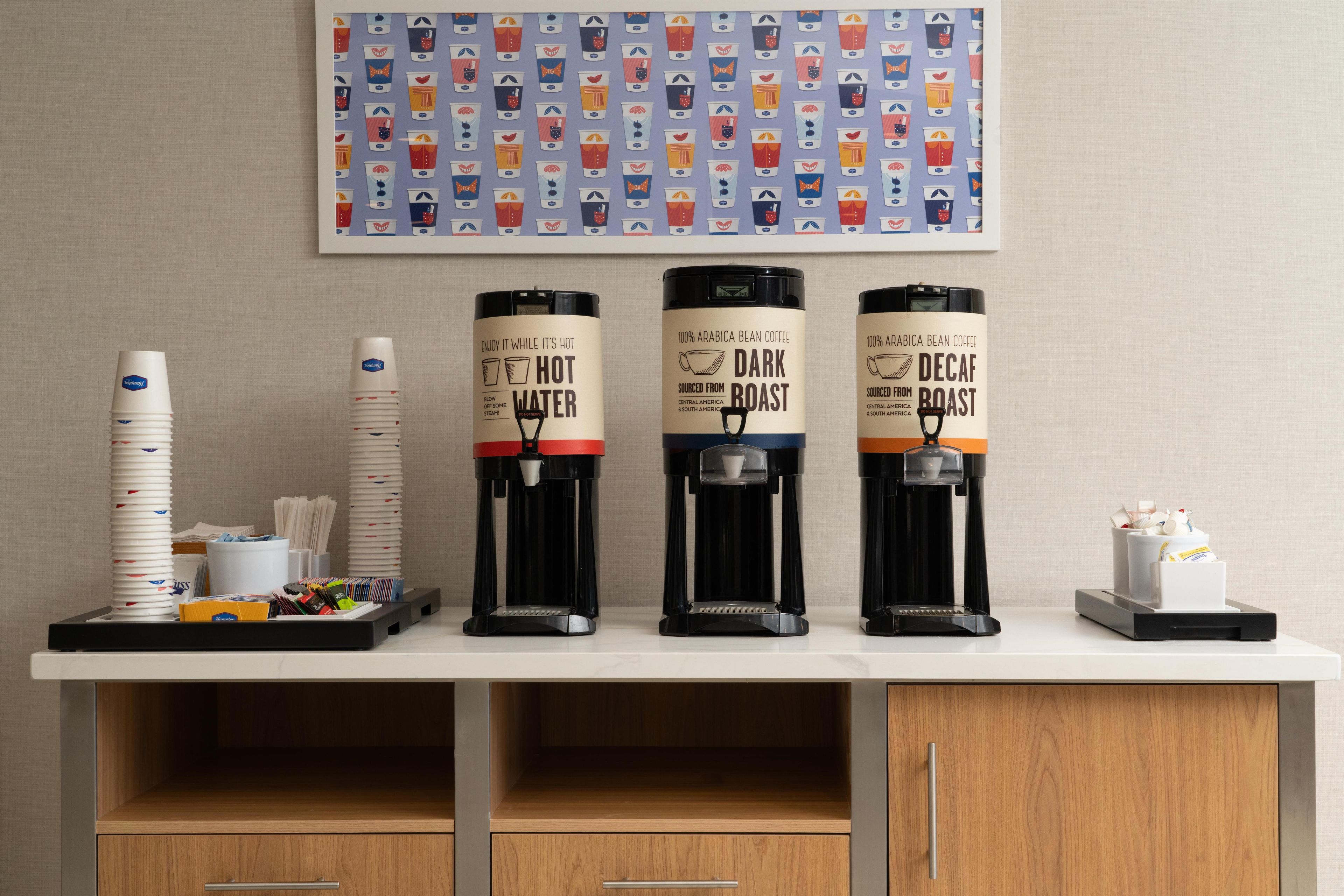 A coffee station with three coffee dispensers labeled 'Hot Water,' 'Dark Roast,' and 'Decaf Roast.'
