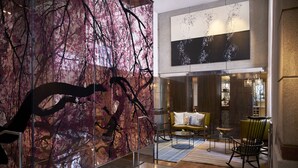 A modern lobby with a large abstract art installation, a seating area with a sofa and chairs, and a glass partition.