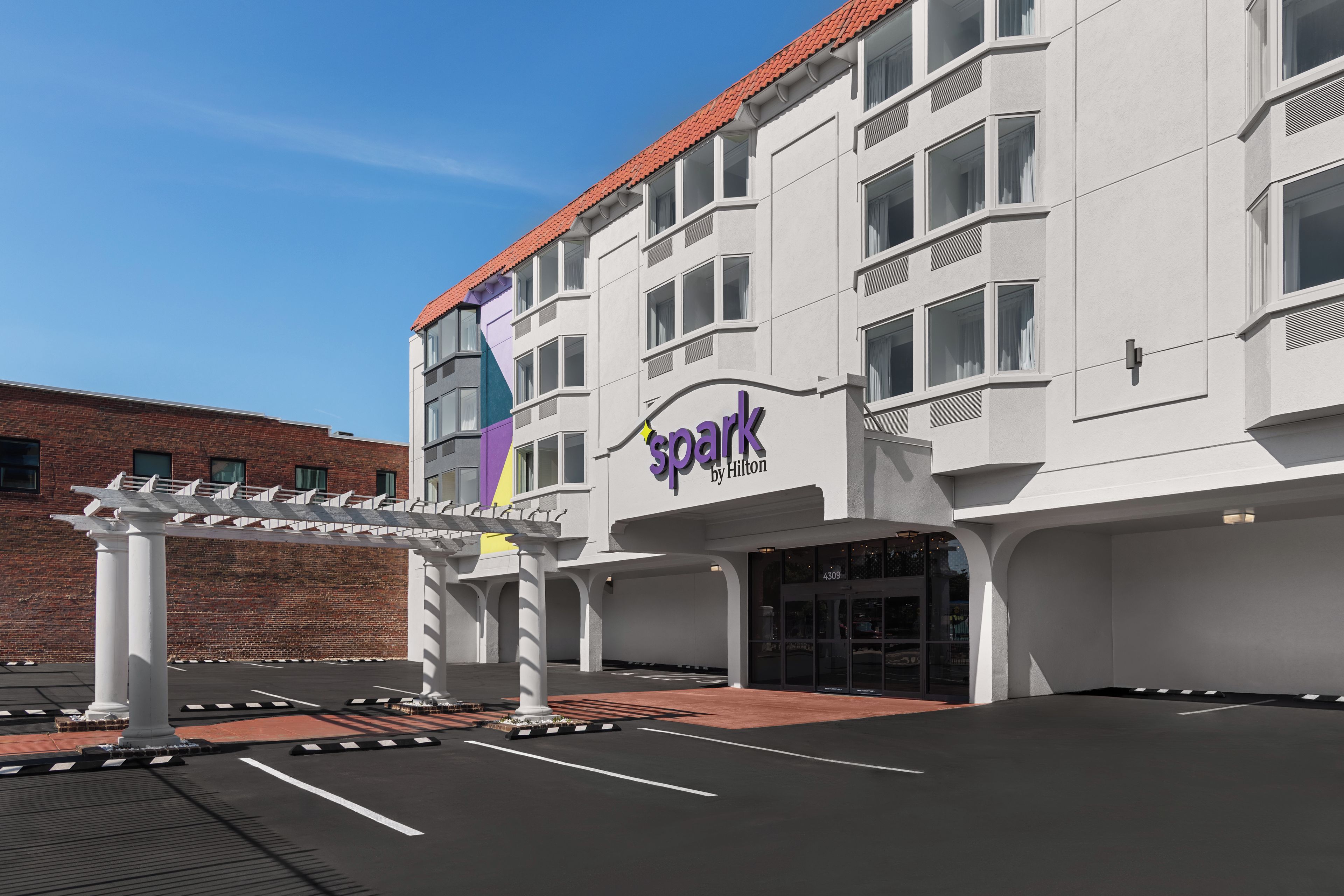 A hotel with a white facade, a red roof, and a sign reading 'Spark by Hilton'.