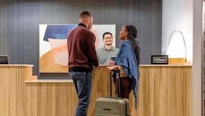 A reception desk with a 'Hilton Honors' sign, a laptop, and a large abstract painting on the wall. - Spark by Hilton Kansas City Plaza Streetcar (Kansas City)