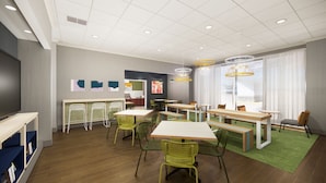 A modern dining area with multiple tables and chairs, a television, and artwork on the walls. - Spark by Hilton Kansas City Plaza Streetcar (Kansas City)
