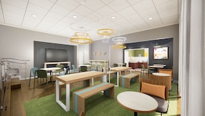A modern meeting room with tables, chairs, and a large screen. - Spark by Hilton Kansas City Plaza Streetcar (Kansas City)