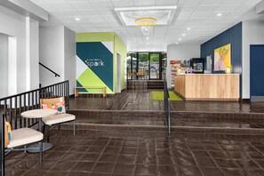 A hotel lobby with a reception desk, seating area, and a staircase leading to an outdoor area. - Spark by Hilton Kansas City Plaza Streetcar (Kansas City)