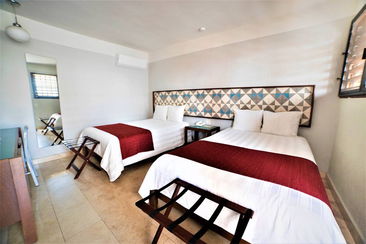 A hotel room with two beds, a desk, and a chair.