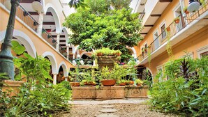 Une cour intérieure avec un jardin central, entourée de balcons et d’arcades.