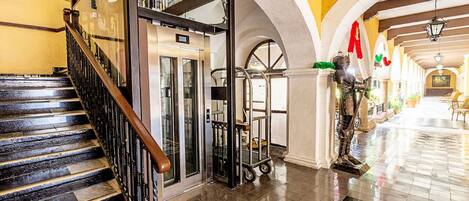 A hotel lobby with a staircase, elevator, and a statue.