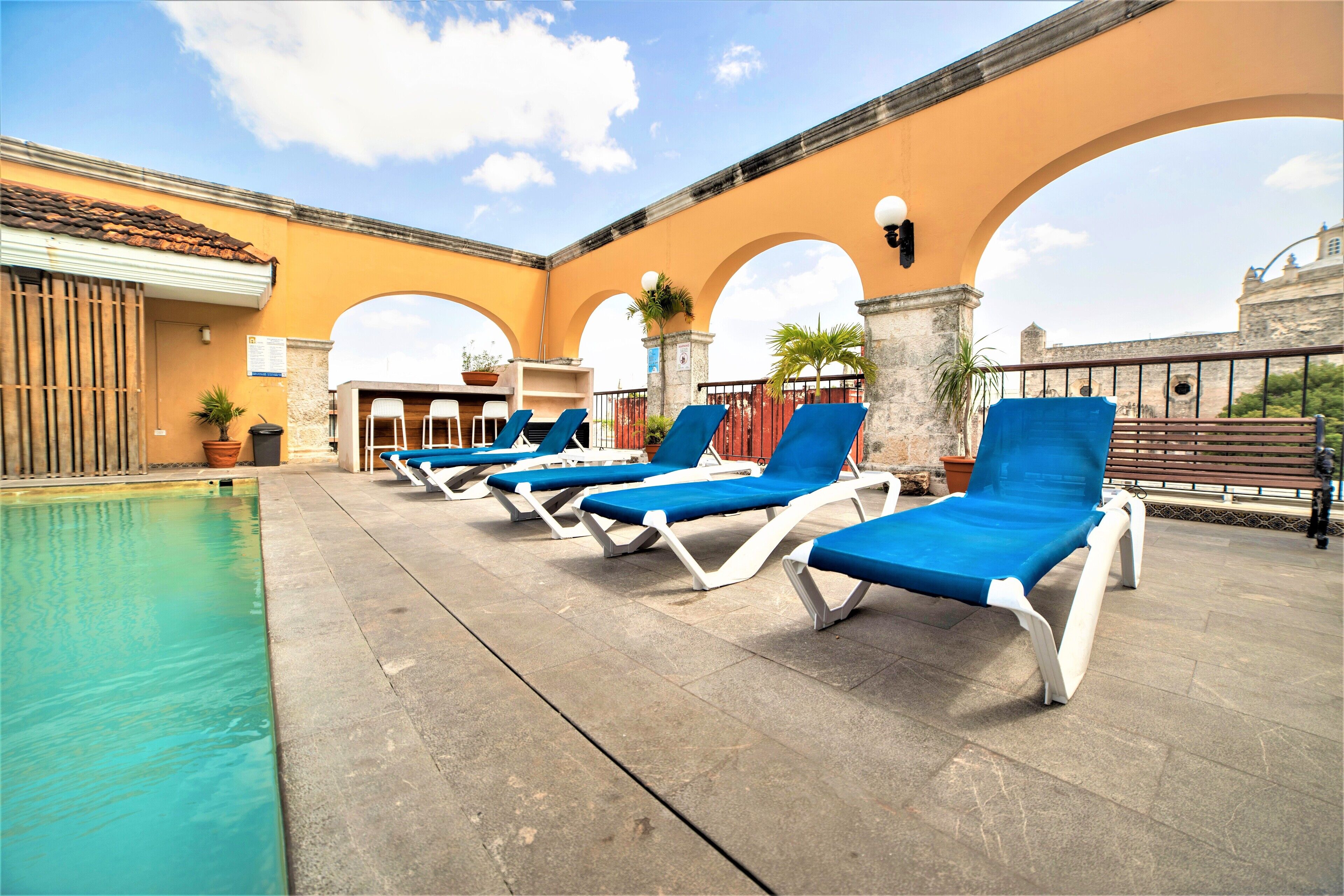 A poolside area with blue lounge chairs and a clear pool.