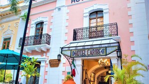 Un bâtiment rose et blanc avec une enseigne indiquant « HÔTEL CARIBE ».