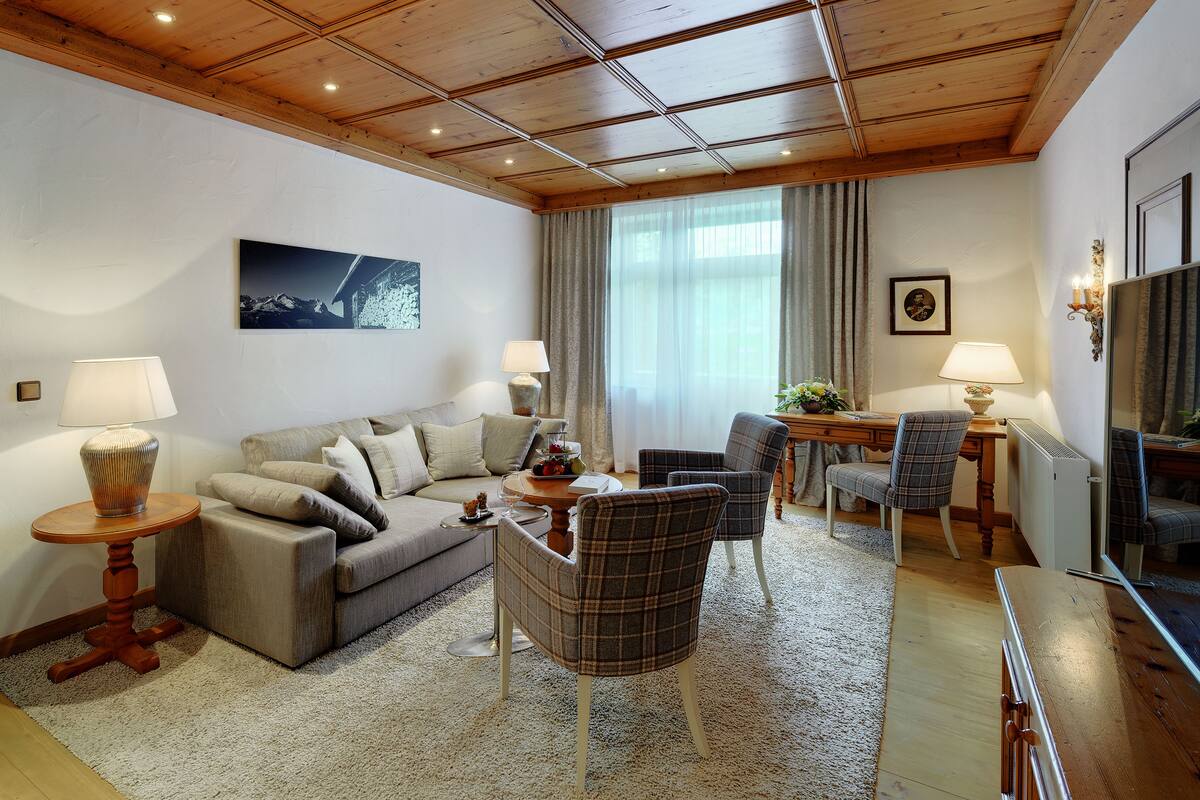 Een goed verlichte woonkamer met een bank, stoelen, een salontafel en een eethoek.