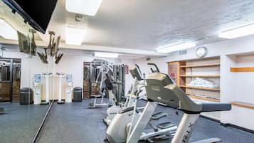 A gym with exercise equipment, a water dispenser, a clock, and a shoe shelf.