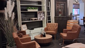 A modern lounge area with leather armchairs, a round coffee table, and a bookshelf.