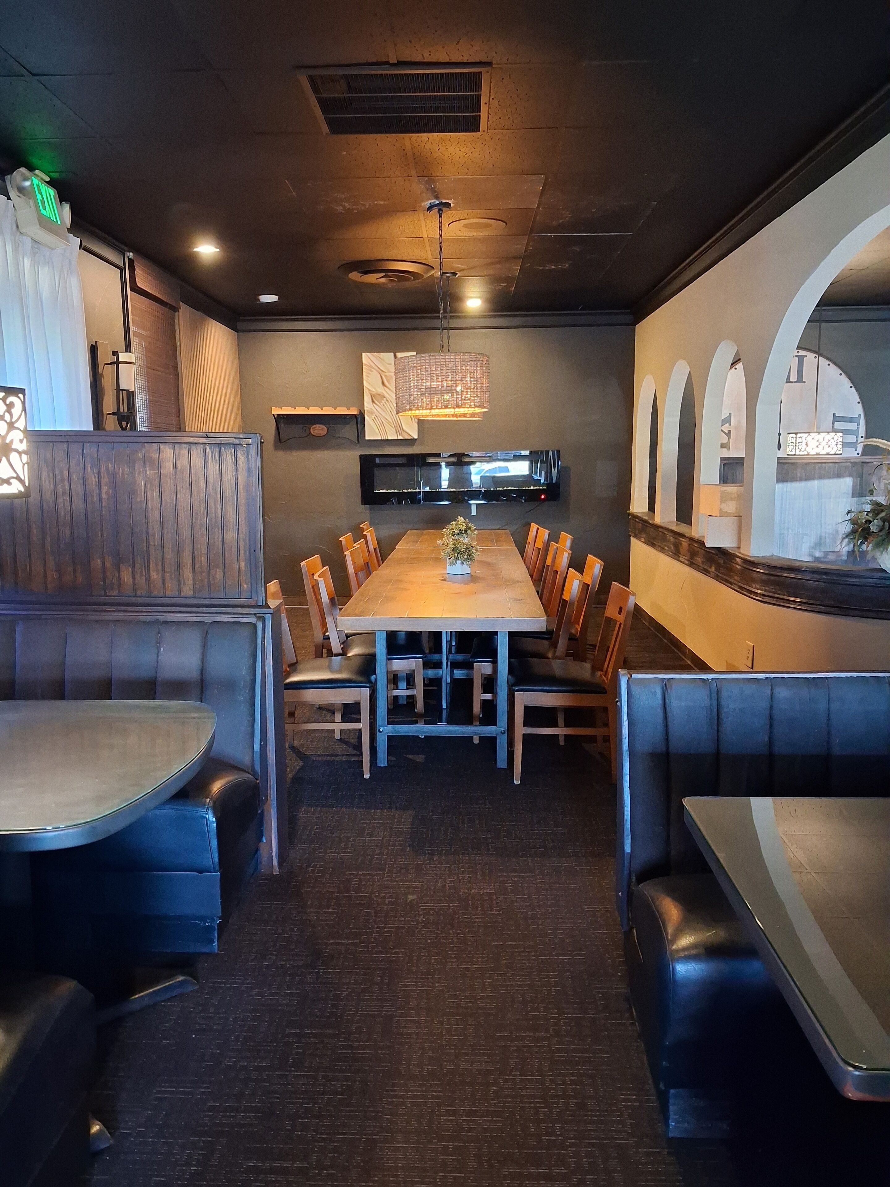 Un restaurante con una mesa larga, cabinas y una pantalla de televisión.
