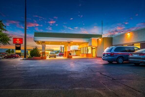 A hotel with a gas station, multiple cars parked, and a clear sky.