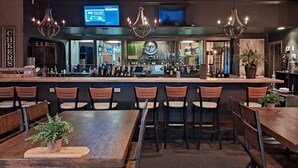A bar area with a counter, bar stools, and a television screen.