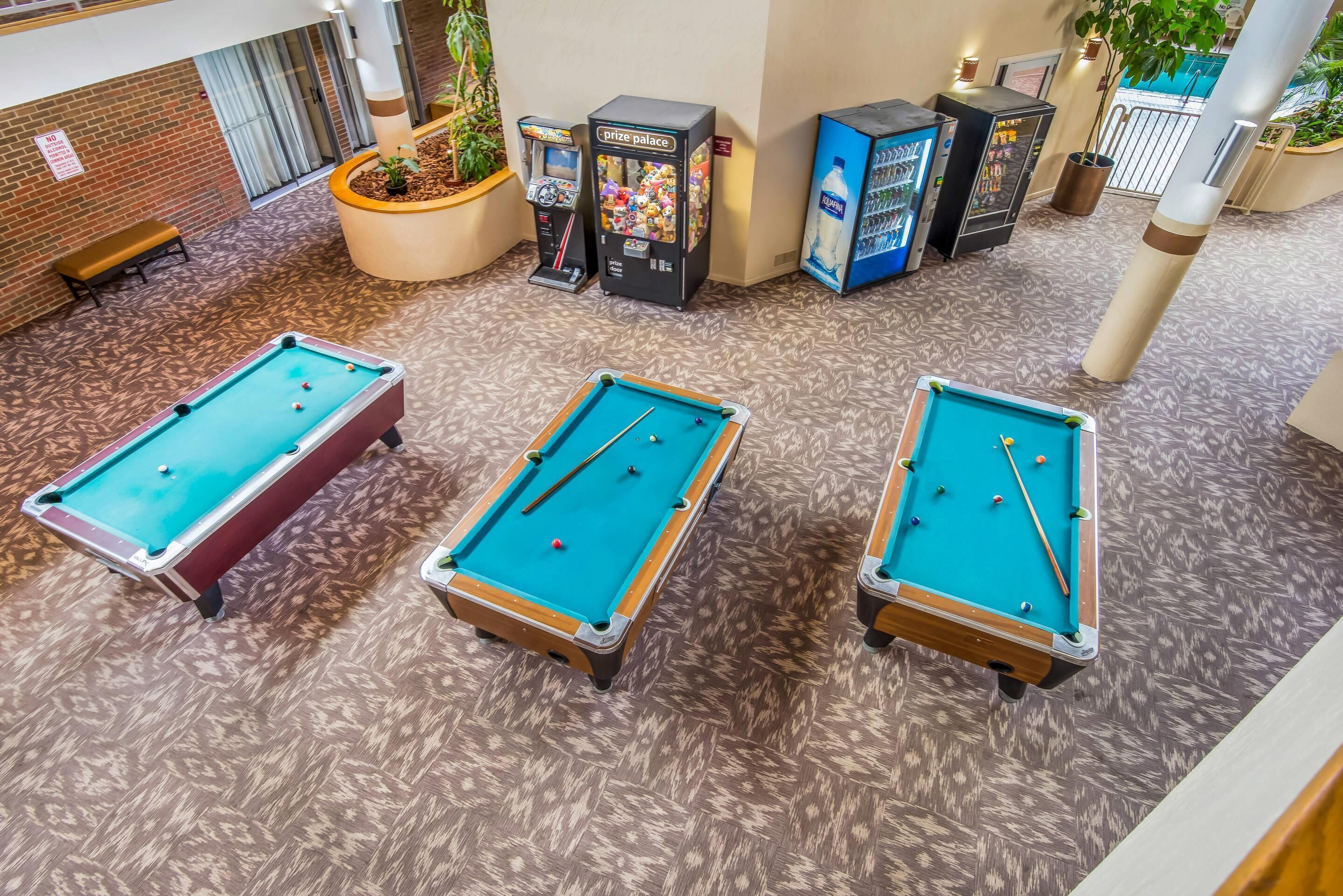 A pool table area with three pool tables, a bench, and vending machines.