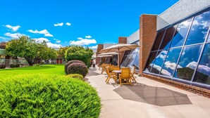 Un patio con mobiliario exterior, un edificio de ladrillo y un césped bien cuidado.