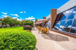 A patio area with outdoor seating, a brick building, and a well-maintained lawn. - Clarion Inn Grand Junction (Grand Junction)