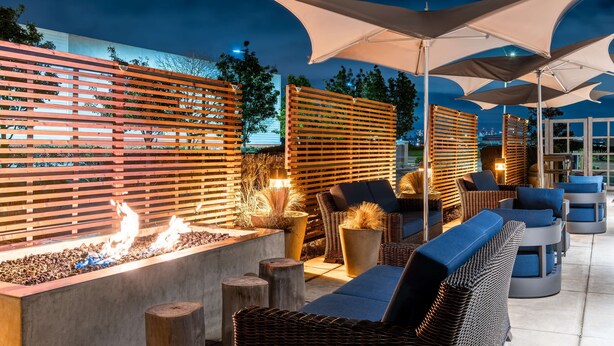 Un espace extérieur aménagé avec des meubles en osier, un foyer et des parasols.