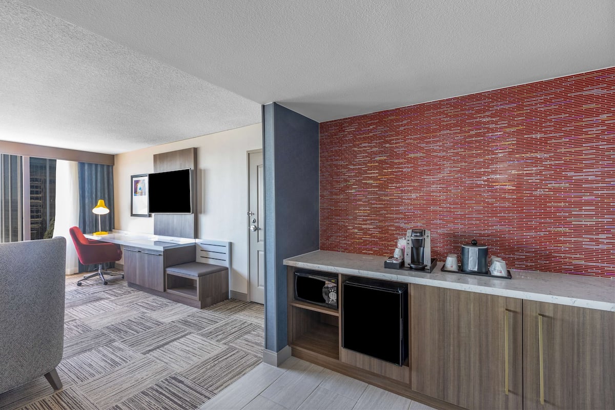 Une chambre d’hôtel moderne équipée d’une kitchenette, d’un bureau, d’une chaise et d’un téléviseur.