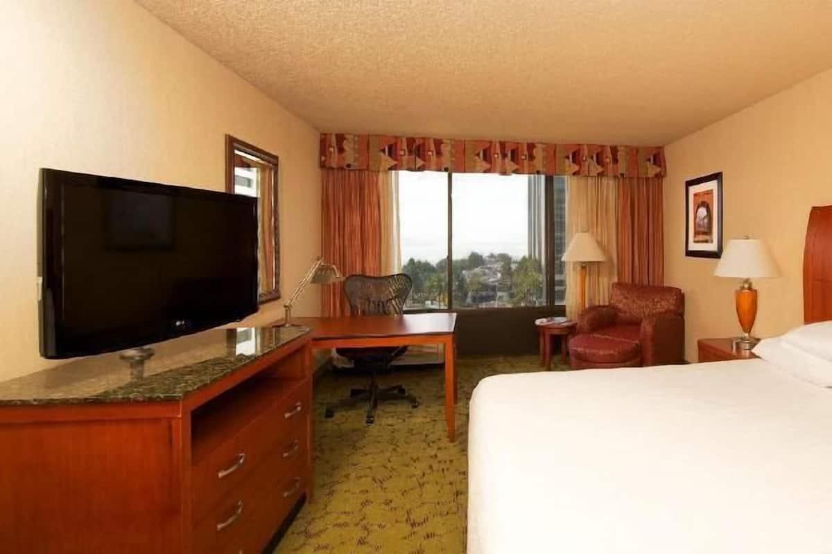 Een hotelkamer met een bed, een bureau, een stoel, een televisie en een raam.