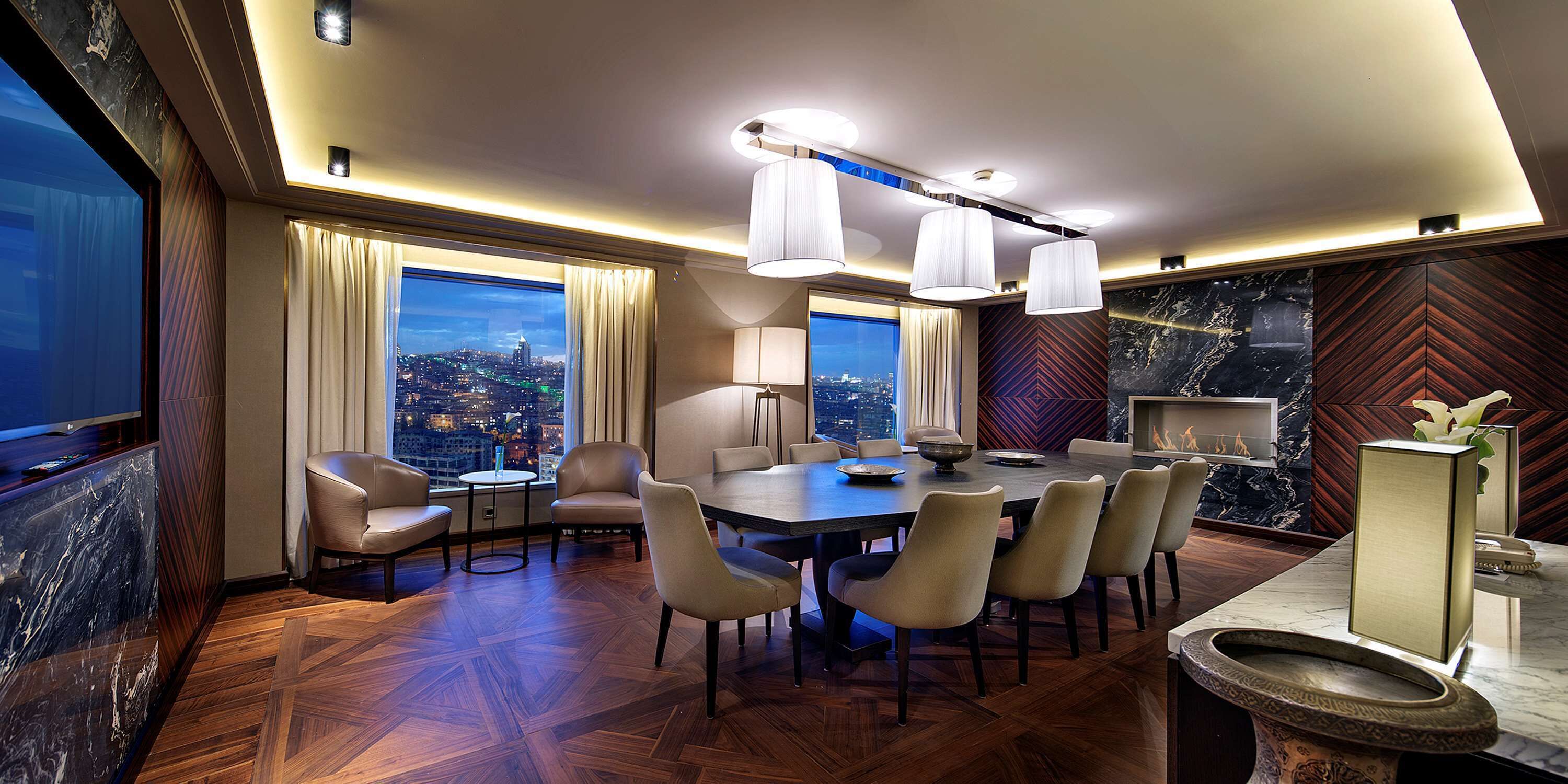 A modern dining area with a large table, chairs, and pendant lighting.