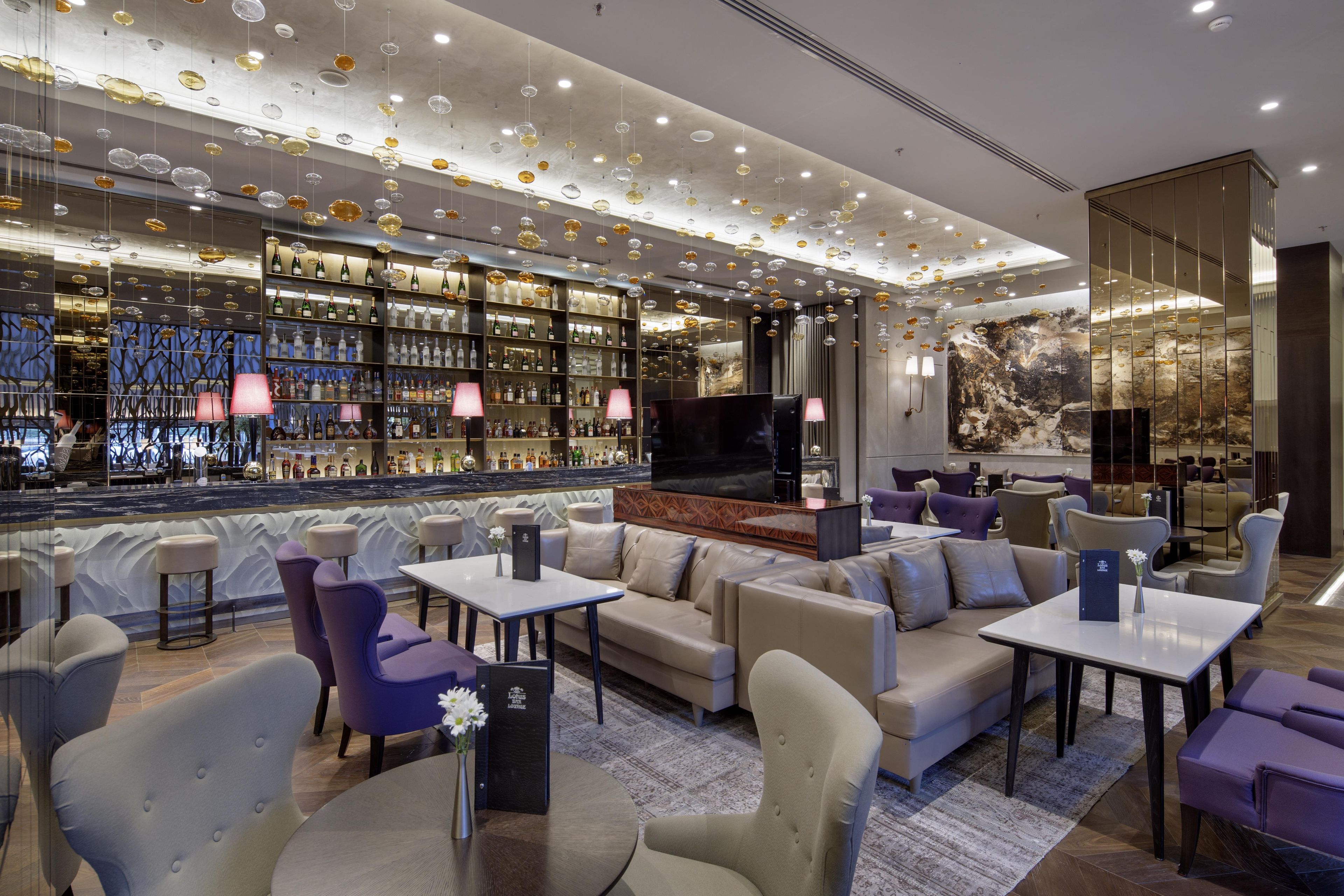 A bar area with shelves of bottles, a television, and seating with tables.