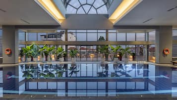 Alberca techada, sombrillas en la alberca y camastros