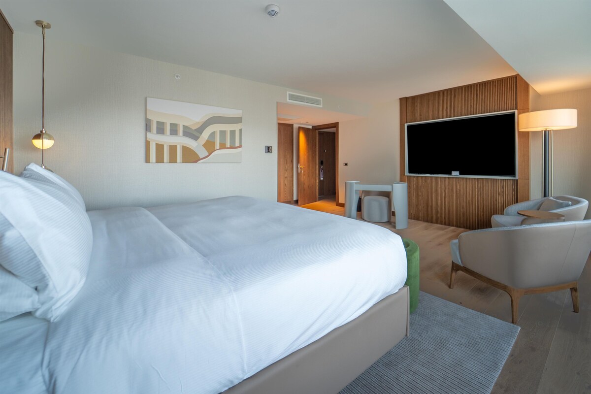 Una camera d'albergo con un letto grande, una TV a schermo piatto, una scrivania e una sedia.
