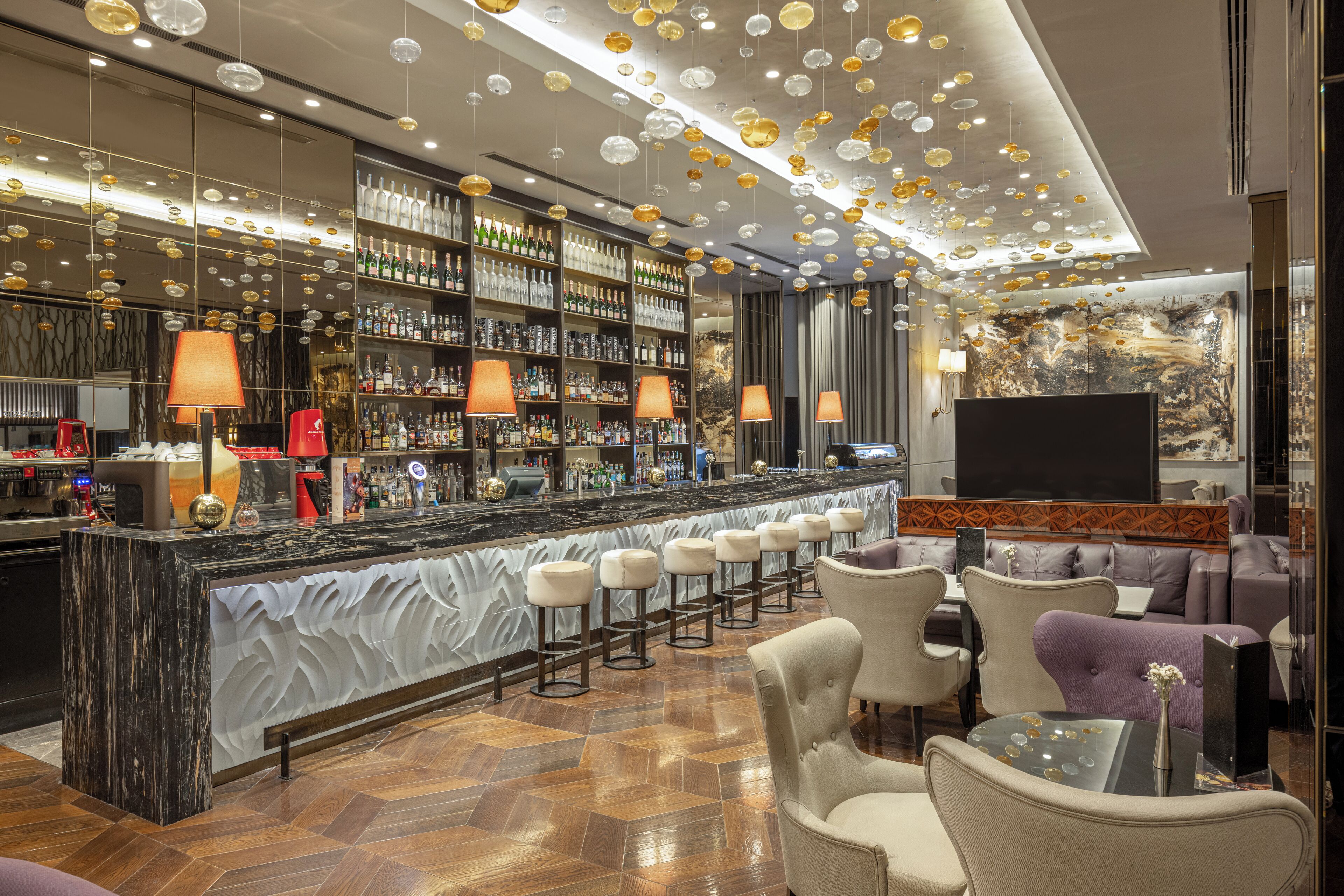 A bar area with a marble countertop, multiple bar stools, and a variety of liquor bottles.