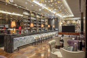 Angolo bar con un bancone in marmo, diversi sgabelli da bar e una varietà di bottiglie di liquore.