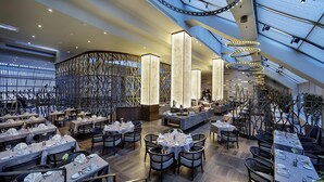 A modern restaurant with multiple dining areas, high ceilings, and contemporary lighting fixtures. - Ankara HiltonSA (Ankara)