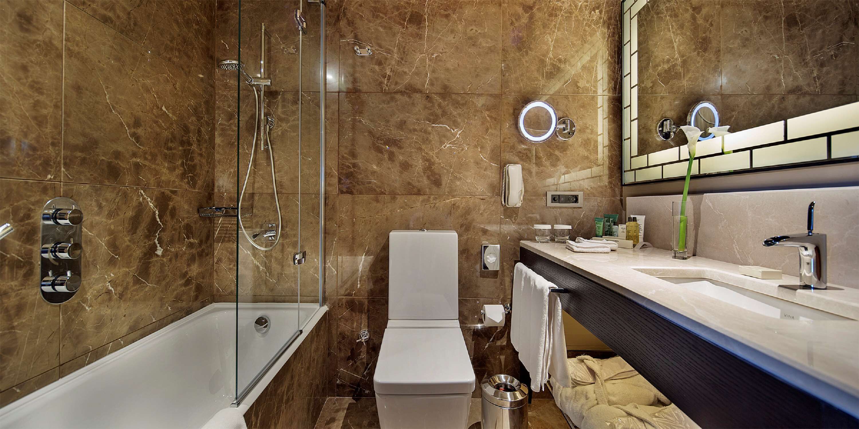 Een moderne badkamer met een douche met glazen wand, toilet en een wastafel met spiegel.