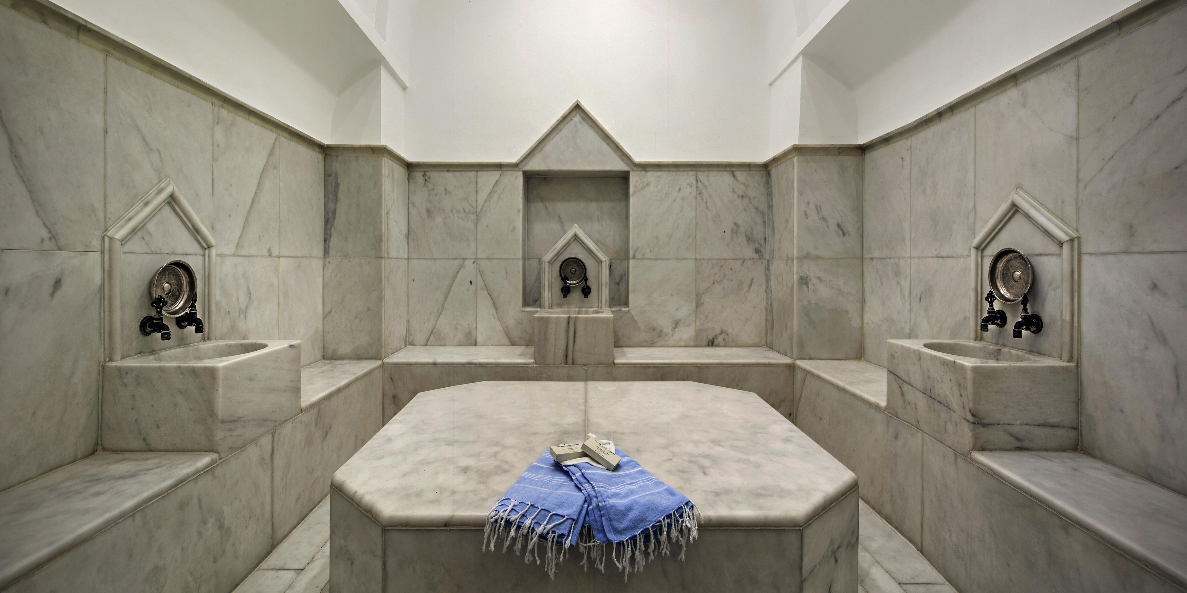 A bathroom with a central sink, two towel racks, and a blue towel on the sink.