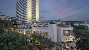 A modern hotel with a tall building, a glass-roofed structure, and a well-lit entrance. - Ankara HiltonSA (Ankara)