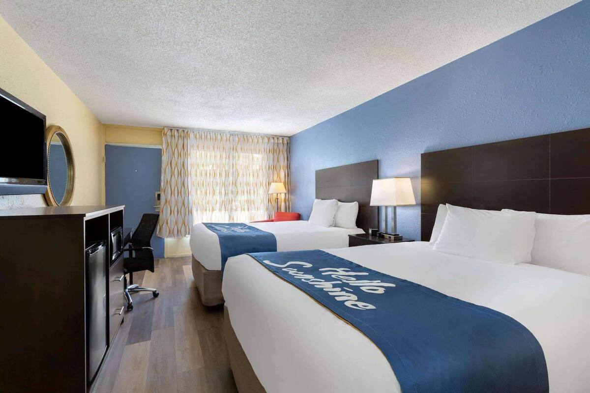 Habitació d'hotel amb dos llits, una taula de treball, una televisió i un bany.