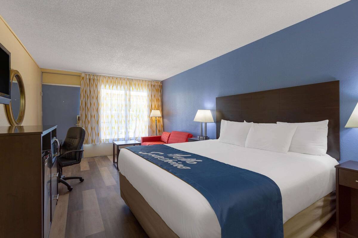 Habitació d'hotel amb un llit gran, un escriptori, una cadira i una televisió.