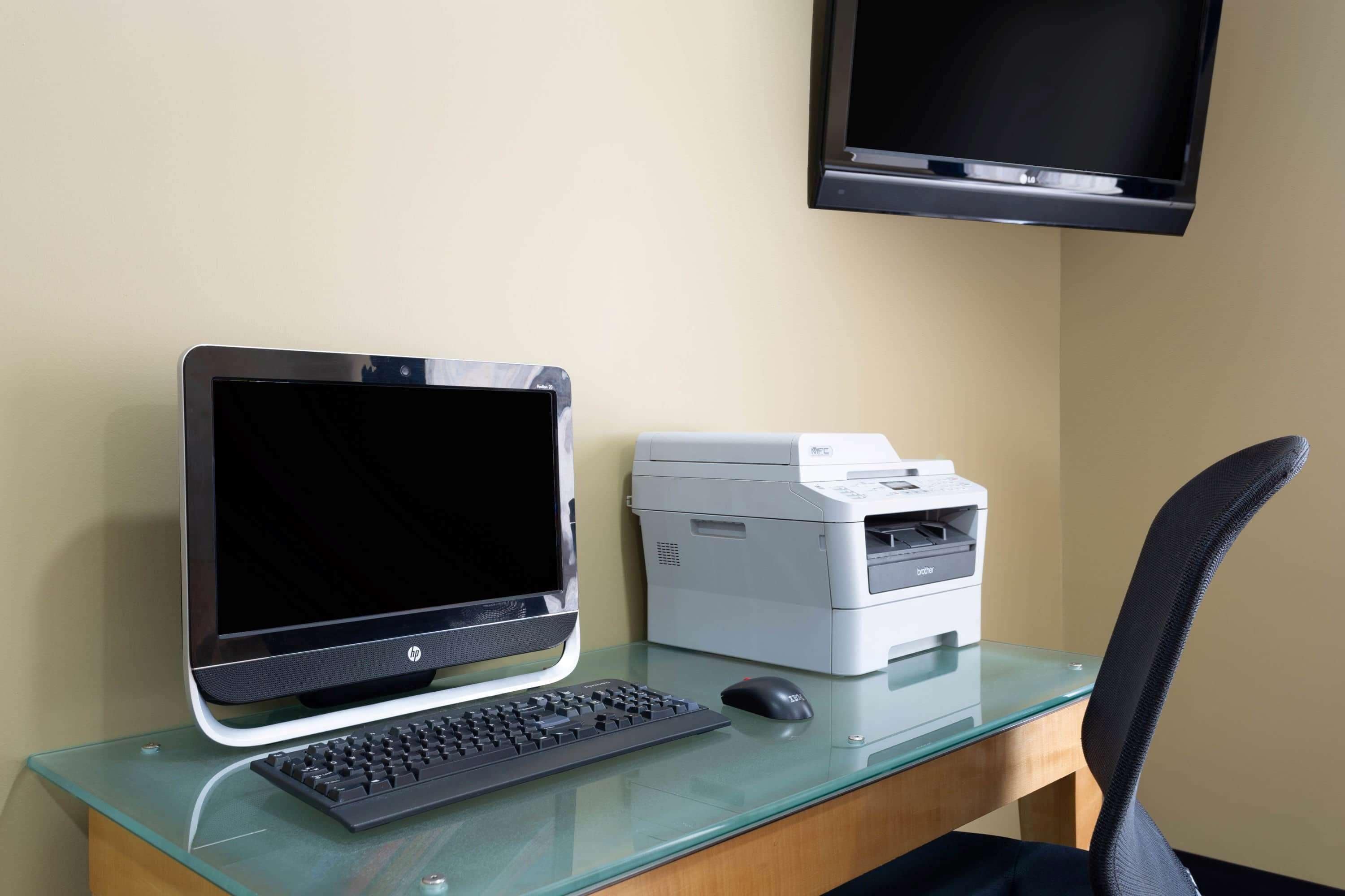 A computer desk with an HP monitor, keyboard, and printer.