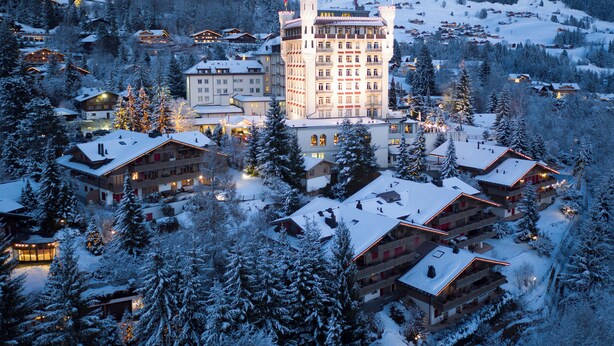 Un pueblo cubierto de nieve con un imponente hotel de estilo castillo, que cuenta con varios balcones y una torre central.