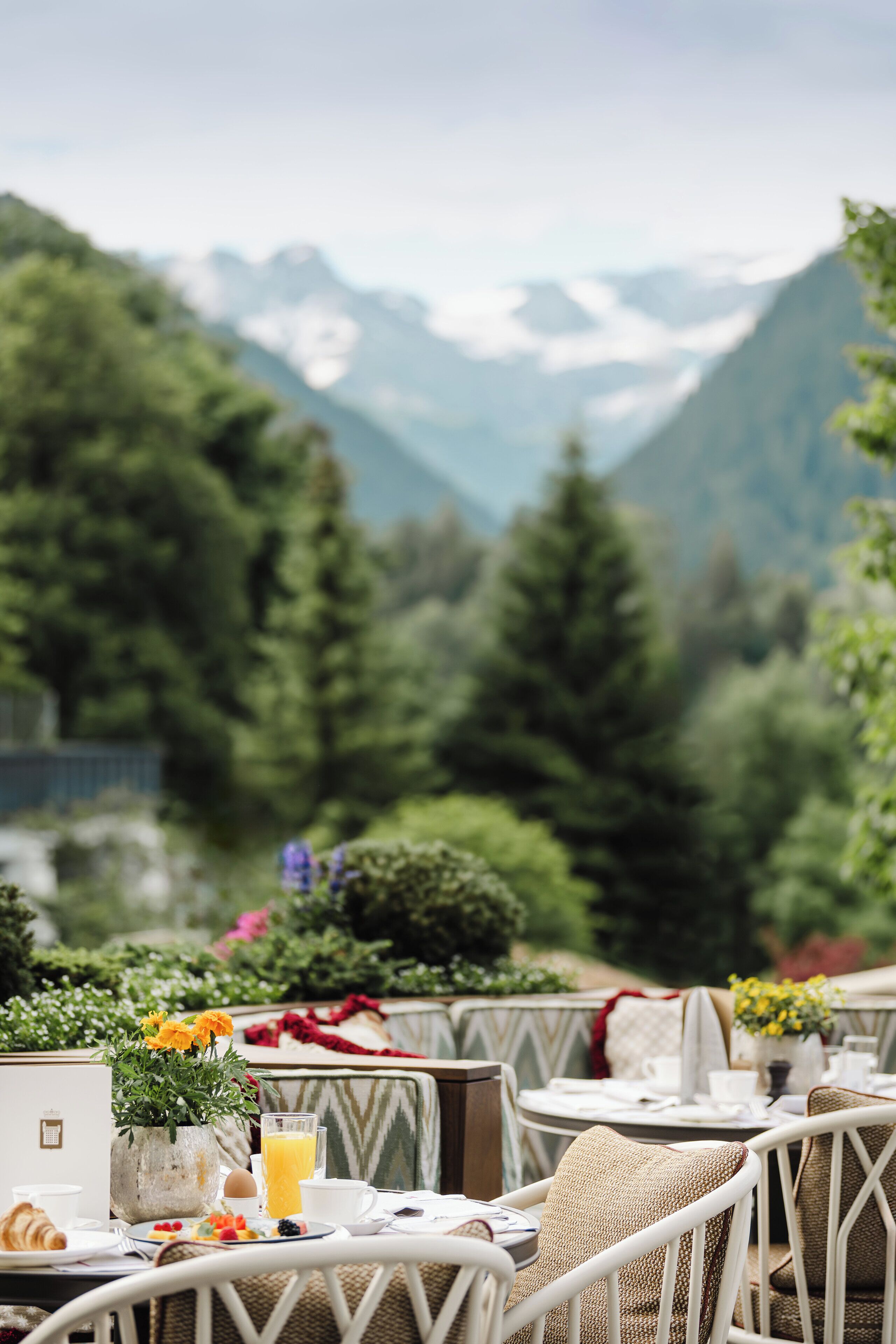 Una mesa servida con alimentos para el desayuno y una computadora portátil, con vistas a un paisaje montañoso.