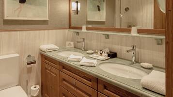 A modern bathroom with a large mirror, two sinks, wooden cabinets, and patterned floor tiles.