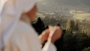 Una persona contempla un paisaje pintoresco con piscina, colinas y cielo despejado.