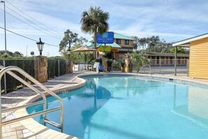 Una piscina al aire libre, sombrillas, sillones reclinables de piscina